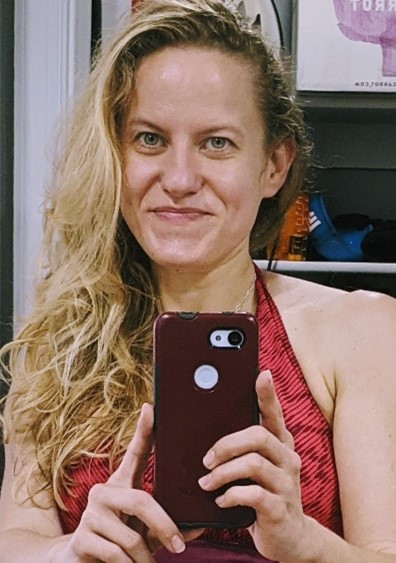 A blonde woman takes a photo of herself with her phone in front of a mirror.