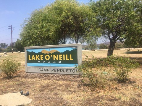 A sign of Lake O’Neill at Camp Pendleton is shown in front of two trees in desert land.