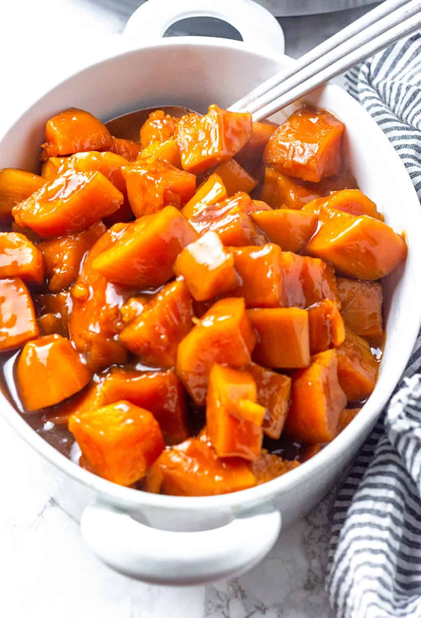 A bowl of diced candied yams similar in appearance to glazed sweet potatoes.