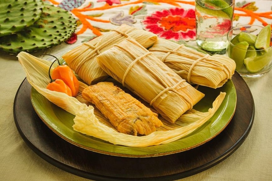A plate serving Cuban tamales wrapped in corn husks.