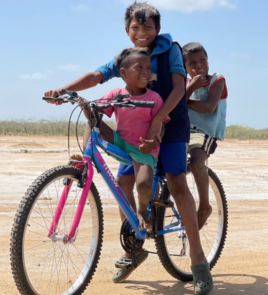 Indigenous Wayuu boys and girls from the North of Colombia riding bikes.