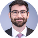 A circular headshot of Travis.